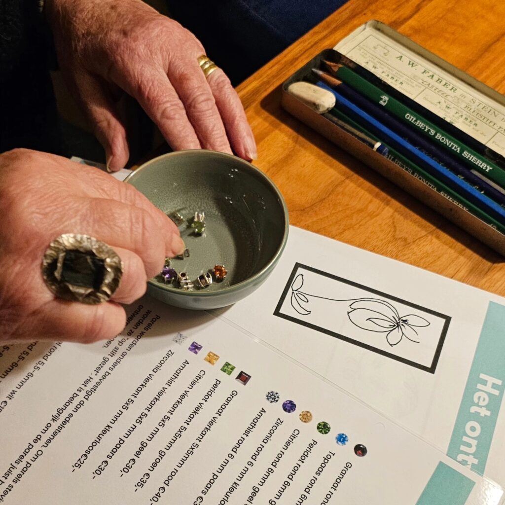 dameshanden die tijdens de workshop in een bakje de juiste edelstenen vist